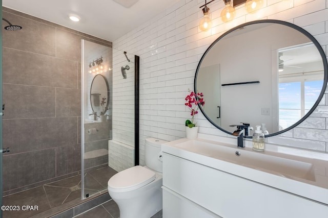 bathroom with toilet, a shower with door, ceiling fan, tile patterned floors, and vanity