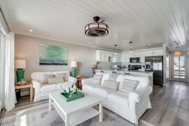 living room featuring sink, light hardwood / wood-style floors, and wooden ceiling