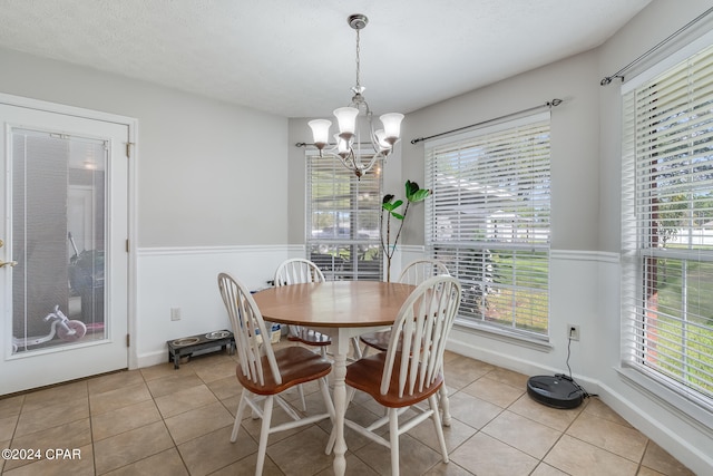 tiled dining space featuring a textured ceiling and a notable chandelier