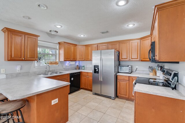 kitchen with sink, kitchen peninsula, a textured ceiling, black appliances, and a kitchen breakfast bar