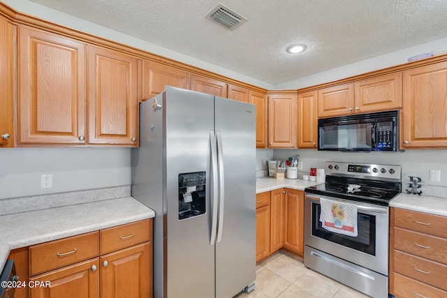 kitchen with a textured ceiling, light tile patterned floors, and stainless steel appliances