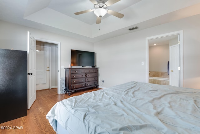 bedroom with connected bathroom, light hardwood / wood-style floors, and ceiling fan