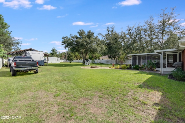 view of yard featuring a sunroom and a fire pit