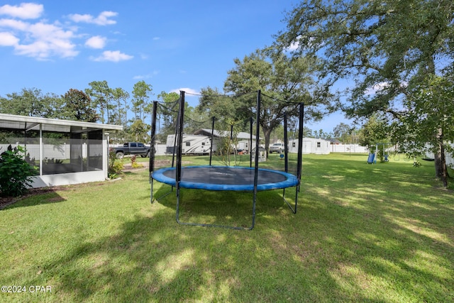 view of yard featuring a sunroom and a trampoline