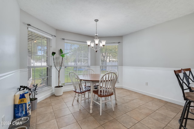 tiled dining room featuring an inviting chandelier, a textured ceiling, and a healthy amount of sunlight