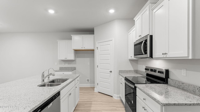 kitchen featuring light stone counters, white cabinets, an island with sink, stainless steel appliances, and light wood-type flooring