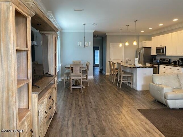 kitchen with hanging light fixtures, a kitchen island with sink, a breakfast bar area, and stainless steel appliances