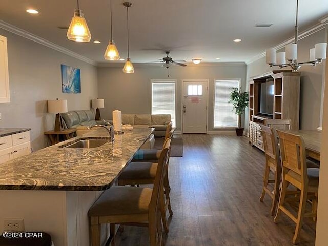 kitchen featuring pendant lighting, sink, white cabinets, a kitchen breakfast bar, and ceiling fan