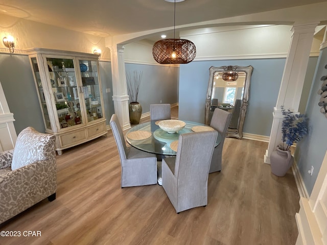 dining space with light wood-type flooring and decorative columns