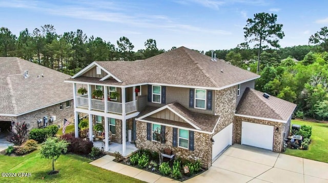 craftsman house with a balcony, a garage, and a front lawn