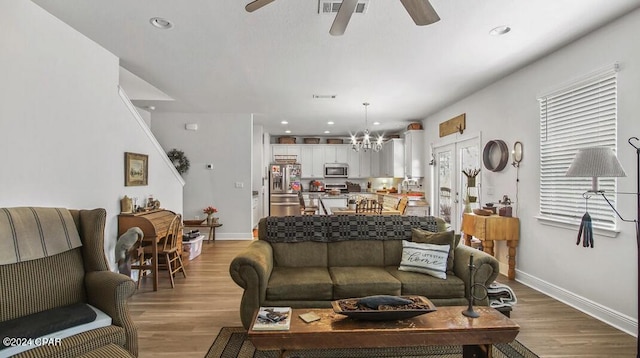 living room with ceiling fan with notable chandelier and light wood-type flooring