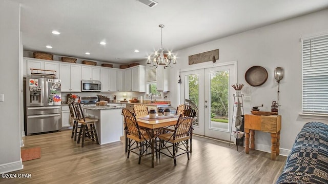 dining area with an inviting chandelier, sink, dark wood-type flooring, and french doors