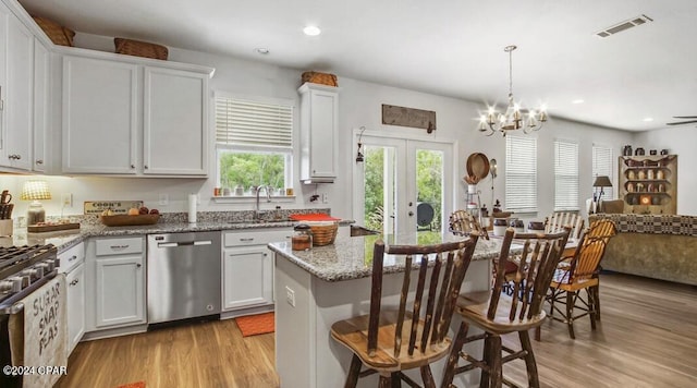 kitchen with light stone counters, light hardwood / wood-style flooring, stainless steel appliances, and white cabinetry