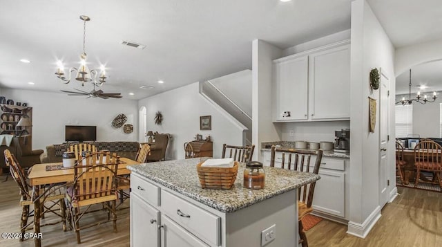 kitchen with light hardwood / wood-style floors, a center island, light stone counters, and white cabinets