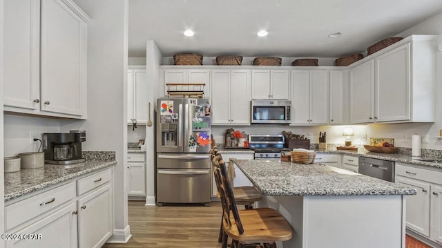 kitchen with a breakfast bar area, white cabinets, a kitchen island, light hardwood / wood-style flooring, and stainless steel appliances