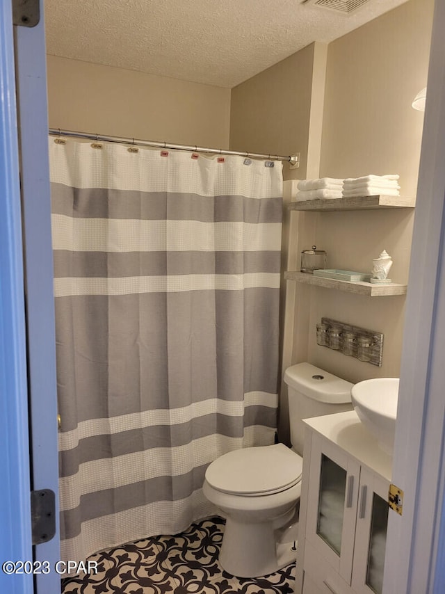 bathroom featuring curtained shower, vanity, a textured ceiling, and toilet