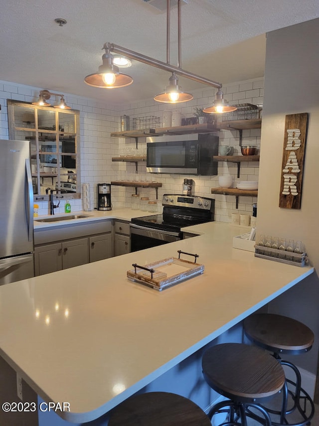 kitchen with stainless steel appliances, decorative backsplash, kitchen peninsula, hanging light fixtures, and sink