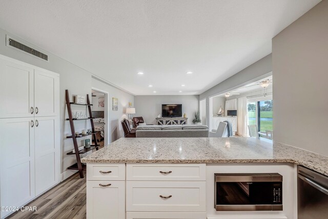 kitchen featuring light stone counters, white cabinetry, light wood-type flooring, and appliances with stainless steel finishes