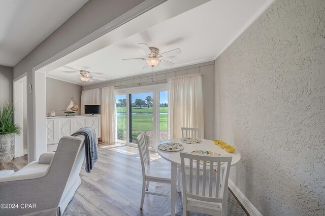 dining space with ceiling fan, crown molding, light wood-type flooring, and a fireplace