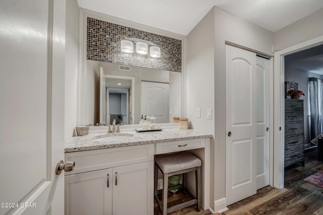 bathroom with hardwood / wood-style floors, vanity, and tasteful backsplash