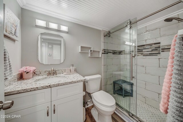 bathroom with hardwood / wood-style floors, toilet, a shower with door, vanity, and ornamental molding