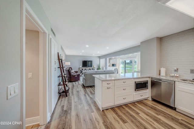 kitchen featuring black microwave, white cabinets, stainless steel dishwasher, kitchen peninsula, and light wood-type flooring