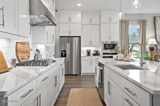 kitchen with sink, appliances with stainless steel finishes, white cabinetry, and an island with sink