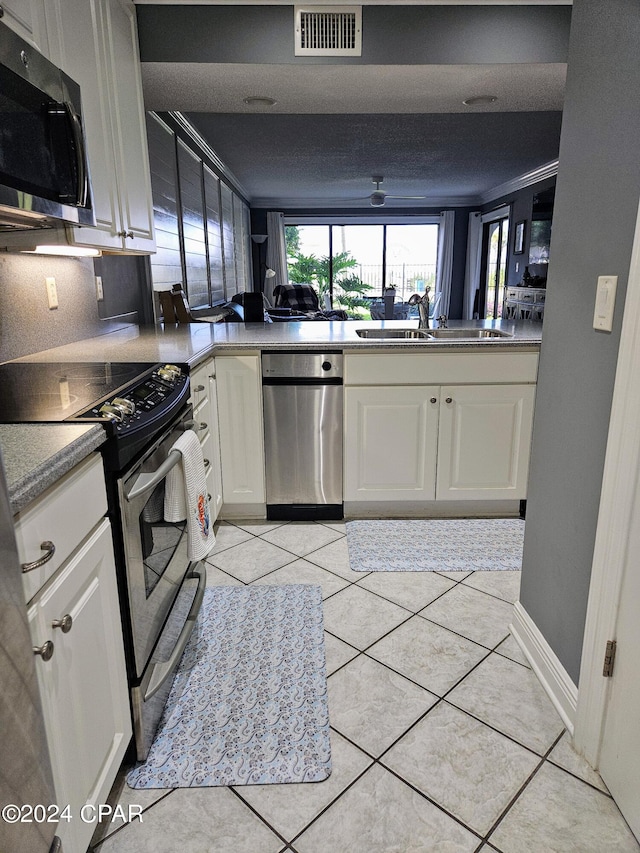 kitchen with white cabinets, sink, light tile patterned floors, kitchen peninsula, and appliances with stainless steel finishes