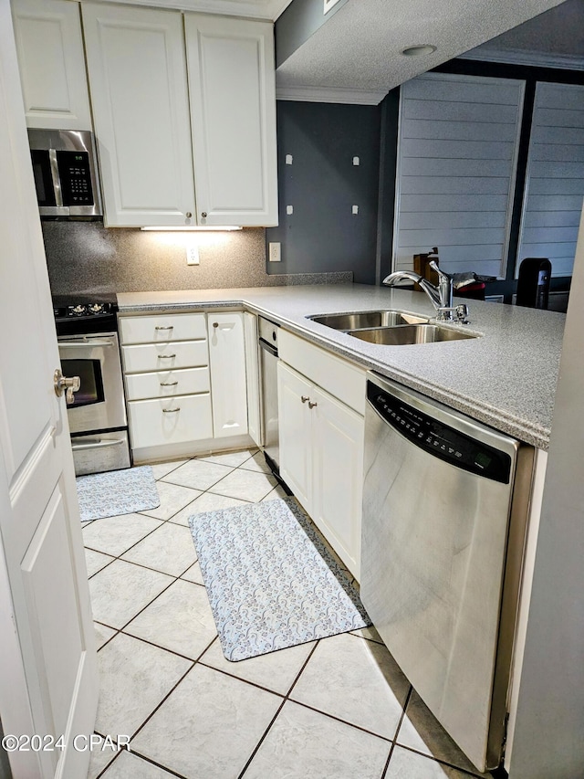 kitchen featuring white cabinets, light tile patterned flooring, sink, a textured ceiling, and stainless steel appliances