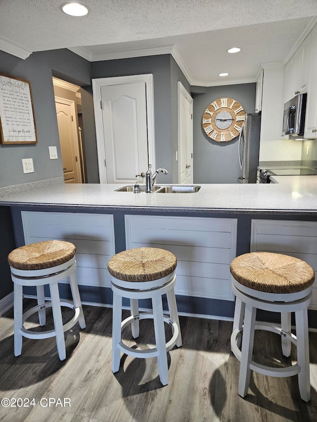 kitchen featuring a kitchen breakfast bar, stainless steel appliances, white cabinetry, and kitchen peninsula