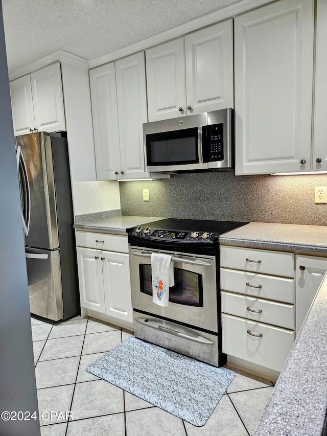 kitchen with white cabinets, a textured ceiling, appliances with stainless steel finishes, and light tile patterned flooring