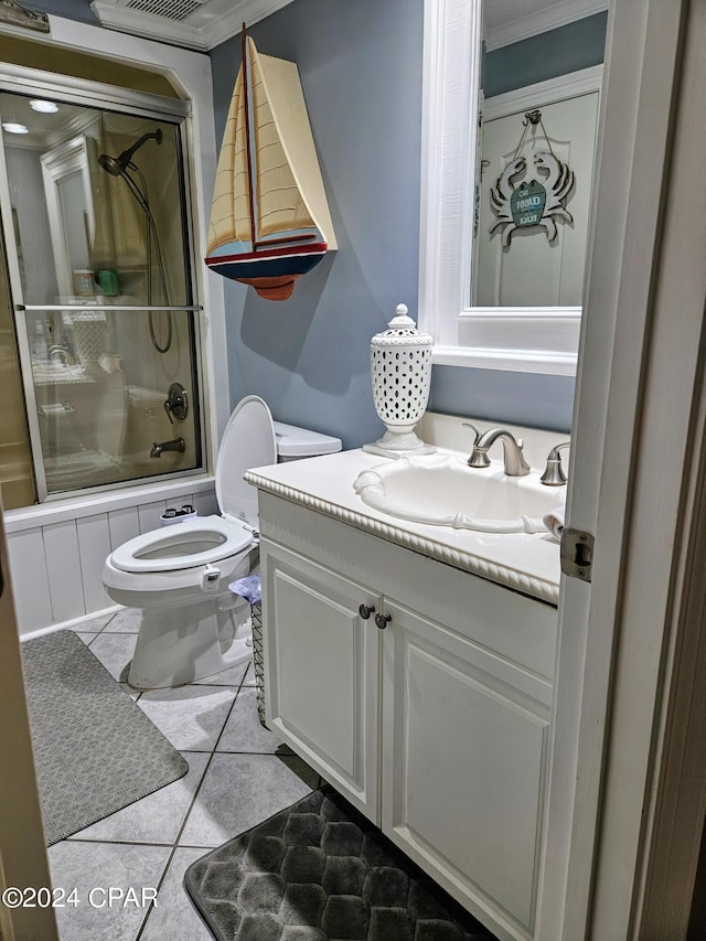 full bathroom with tile patterned floors, crown molding, bath / shower combo with glass door, vanity, and toilet