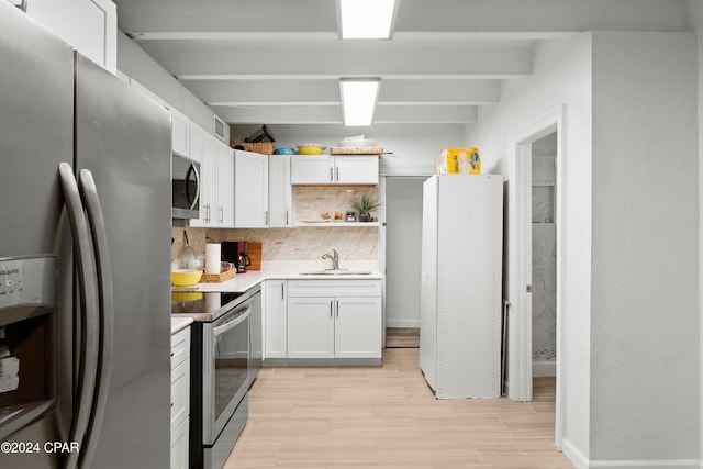 kitchen with stainless steel appliances, sink, tasteful backsplash, beam ceiling, and white cabinetry