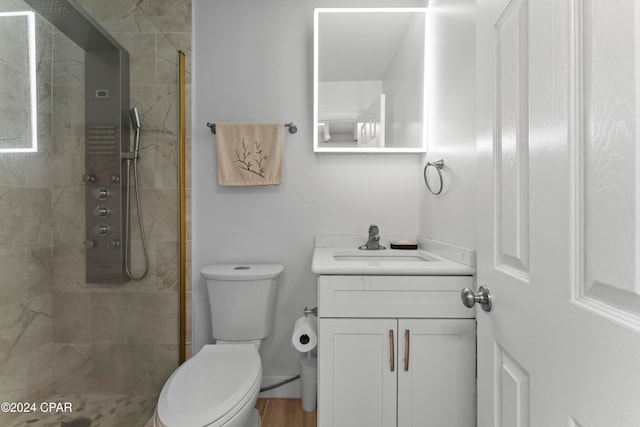 bathroom with a tile shower, vanity, hardwood / wood-style flooring, and toilet