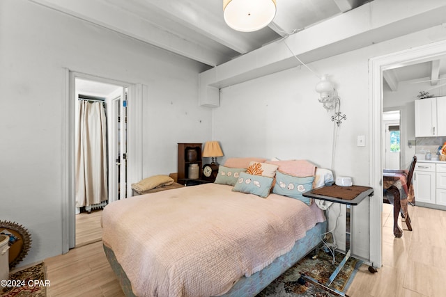 bedroom with light wood-type flooring and beam ceiling