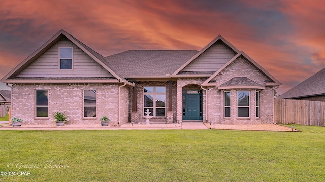 back house at dusk featuring a lawn