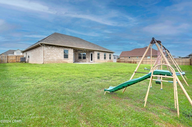 back of property with a playground, a lawn, and central AC unit