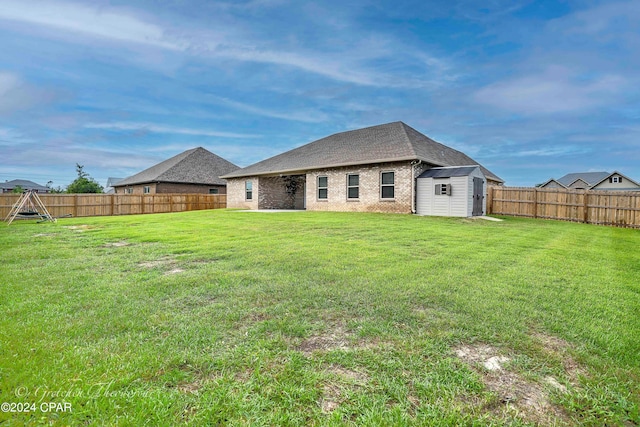 rear view of property featuring a storage unit and a yard