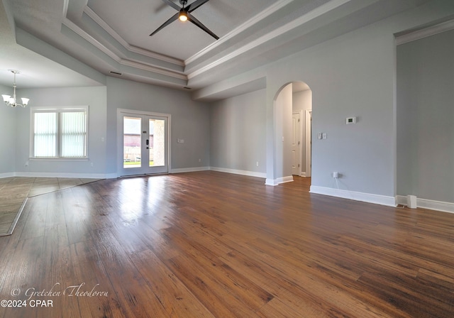 unfurnished room with ceiling fan with notable chandelier, a raised ceiling, dark hardwood / wood-style floors, and crown molding