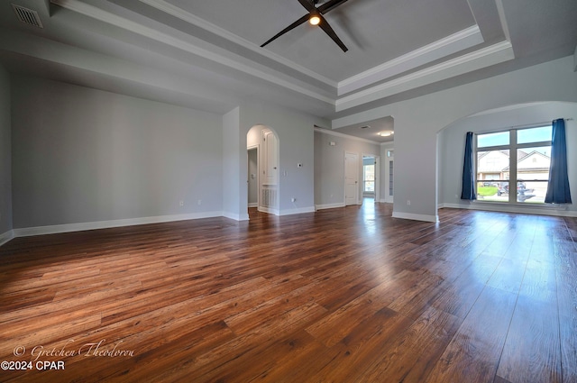 spare room featuring a tray ceiling, ceiling fan, dark wood-type flooring, and crown molding