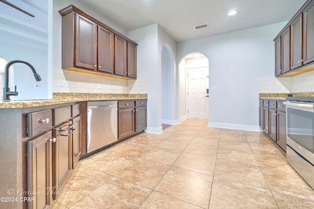 kitchen with light stone counters, sink, decorative backsplash, stainless steel appliances, and light tile patterned floors