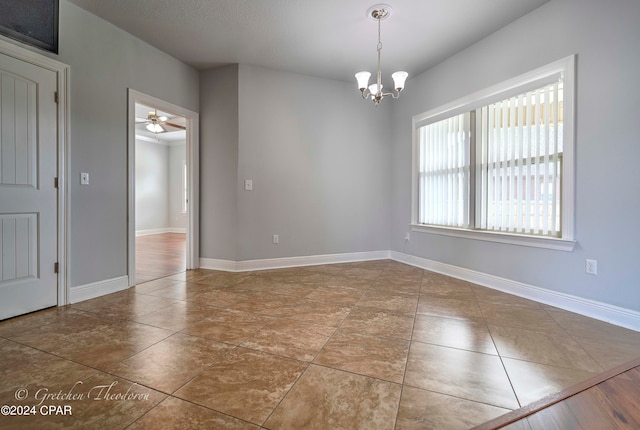 tiled spare room with ceiling fan with notable chandelier