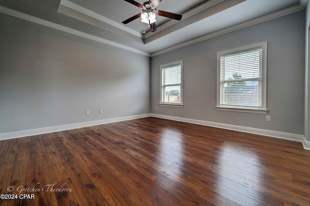 empty room featuring ceiling fan, a raised ceiling, crown molding, and dark wood-type flooring