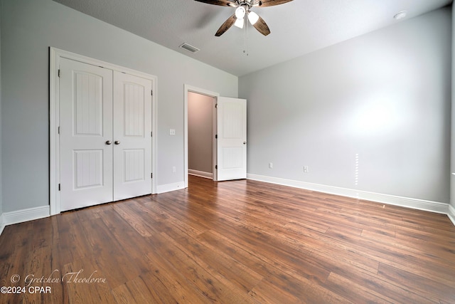 unfurnished bedroom featuring a closet, ceiling fan, dark wood-type flooring, and a textured ceiling