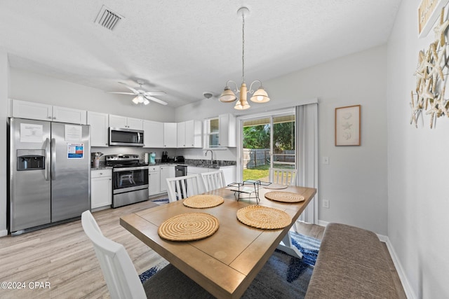 dining space with sink, ceiling fan with notable chandelier, a textured ceiling, and light hardwood / wood-style floors