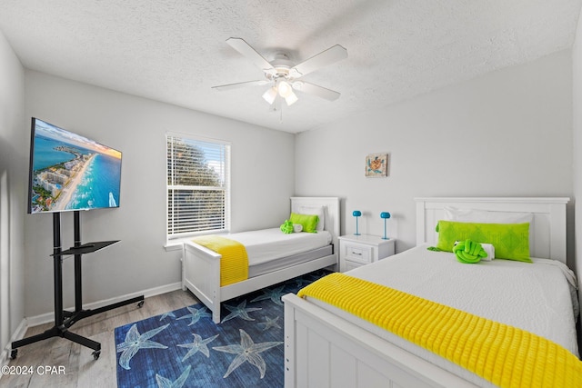 bedroom with ceiling fan, a textured ceiling, and dark hardwood / wood-style floors