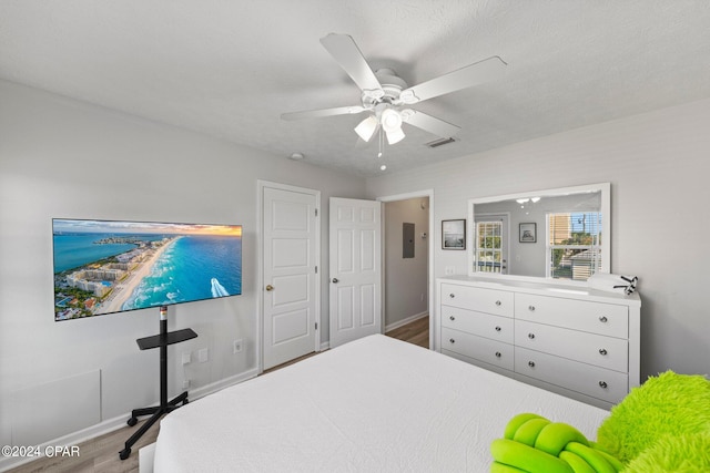 bedroom with ceiling fan, wood-type flooring, and a textured ceiling