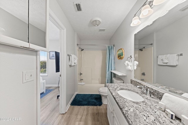 full bathroom with toilet, wood-type flooring, vanity, a textured ceiling, and shower / bathtub combination with curtain