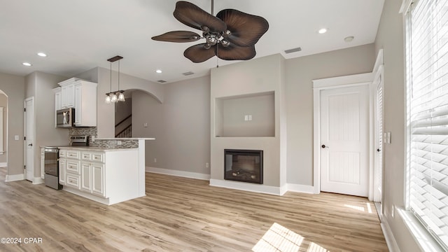 kitchen featuring hanging light fixtures, light hardwood / wood-style floors, white cabinets, stainless steel appliances, and ceiling fan