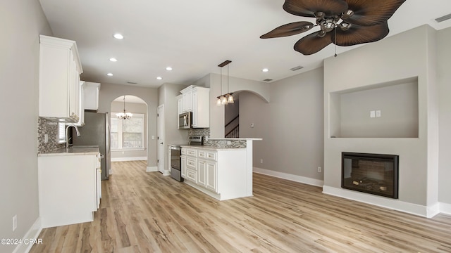 kitchen featuring appliances with stainless steel finishes, hanging light fixtures, white cabinetry, tasteful backsplash, and light wood-type flooring